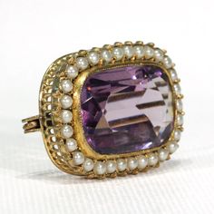 This mid to late Victorian brooch was lovingly handcrafted in 9 karat gold and is set with a stunning, deep purple rectangular cushion cut amethyst. Bezel set, with a fine millegrain border this jubbly gem measures 21.8 x 14 x 7.1 mm, and has estimated carat weight of an impressive 12.6 carats. Sitting atop a fine, hand pierced gallery, it is surrounded by a single row of thirty fine natural pearls. This exquisite jewel was most likely made between 1870 and 1880, and though unmarked it has been Thirty Fine, Hand Piercing, Victorian Brooch, Rectangular Cushion, Memorial Ring, Sapphire Band, Pearl Brooch, Spring Green, Antique Jewellery