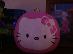 a hello kitty pumpkin sitting on top of a wooden table next to a framed photo