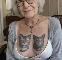 an older woman with tattoos on her chest and cat pictures on her chest is looking at the camera