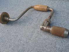 an old metal handlebar with wooden handles on carpeted floor next to wall mounted toilet paper dispenser