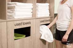 a woman standing in front of a display of towels and folded towels on wooden shelves