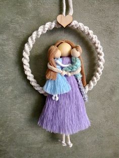 an ornament is hanging on the wall with two dolls in it's arms