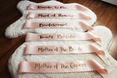 four pink ribbons with names on them sitting on a white rug in front of a wooden floor