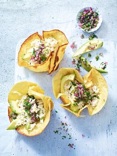 three tacos filled with toppings sitting on top of a table