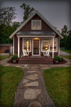 a small house is lit up at night with lights shining on the porch and lawn