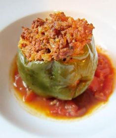 an artichoke stuffed with meat and sauce on a white plate