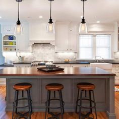 a kitchen island with three stools in front of it