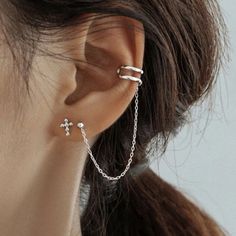 a close up of a person wearing some kind of ear chain with cross on it