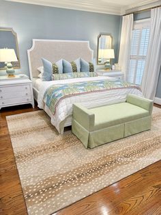 a large bed sitting on top of a wooden floor next to a white dresser and chair