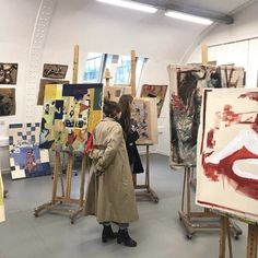 a woman standing in front of paintings on easels