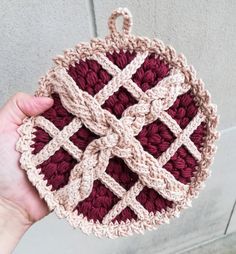 a hand is holding a crocheted dishcloth in the shape of a square