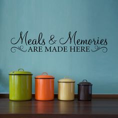 three colorful canisters sitting on top of a wooden table next to a wall