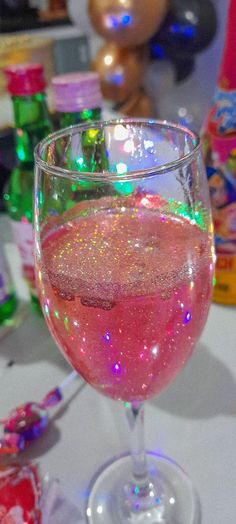 a wine glass filled with pink liquid on top of a table next to candy bars