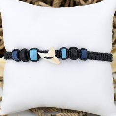 a white starfish on a black beaded bracelet with blue beads and an anchor