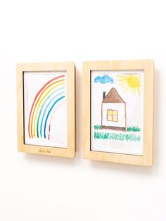 two wooden frames with drawings on them hang on the wall next to each other in front of a white background