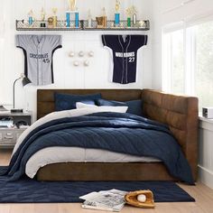 a baseball jersey hangs on the wall above a bed in a room with hardwood floors