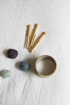 yarn and wooden skewers on white tablecloth with cotton balls in the foreground