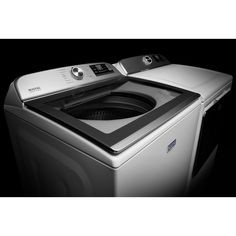 a silver washer sitting on top of a dryer in front of a black background