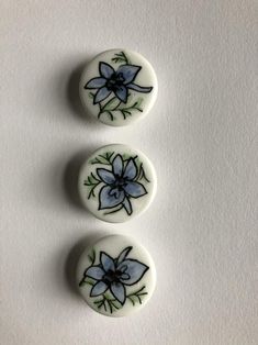 three white buttons with blue flowers on them