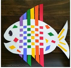 a fish made out of colored paper sitting on top of a wooden table