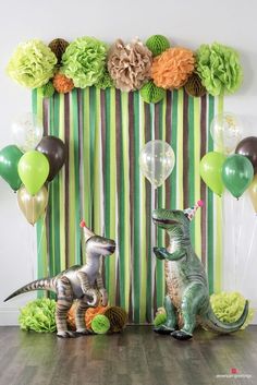 two dinosaur figurines sitting next to each other in front of balloons and streamers