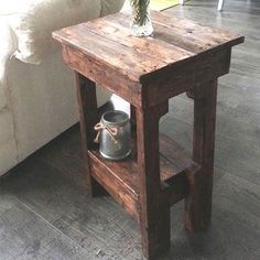 a small wooden table sitting on top of a hard wood floor next to a white couch