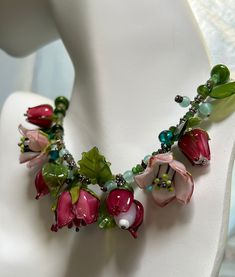 One of a kind Flower Garden Necklace. Designer Handmade Original. Exquisite handmade glass flowers. Extraordinarily lifelike flowers and leaves of Rose Red, Pink and Green glass. are truly an art form. The flowers are roses, fuschias and tulips. One of the larger light pink roses was accidentaly broken in the making of the necklace but I repaired it and it's very difficult to see the place. I have combined the flowers and leaves with natural green garnets and green glass beads.  Sterling silver hook clasp and decorative beads. This would be a stunning gift for a woman who loves to garden. I think this is one of the prettiest necklaces I have ever made. I love looking at it. When it's not being worn it should be displayed like a piece of art. There is only one. Unique Glass Jewelry For Wedding, Elegant Glass Flower Necklaces, Elegant Glass Flower Necklace, Elegant Flower Shaped Glass Necklaces, Elegant Flower-shaped Glass Necklaces, Whimsical Red Flower Jewelry, Green Pink Flowers, Designer Glass, Valley Village