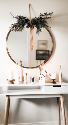 a white table topped with a round mirror and christmas decorations next to a candle holder