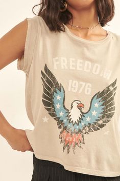 Mineral washed graphic t-shirt. Vintage-style American eagle graphic print with "Freedom 1976" text. Cut-off sleeves with raw edge. Round neckline. Distressed detailing at neckline and hem. Relaxed fit. 100% Cotton. Imported top designed and printed in LA. Model wears size S. Sleeveless Graphic Tee, Eagle Graphic, Graphic Tops, Vintage Canvas, Raw Edge, Round Neckline, Graphic Prints, Graphic Tee, Vintage Style