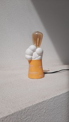 a yellow and white light bulb sitting on top of a table next to a wall