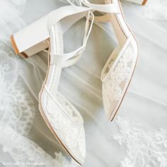 a pair of white wedding shoes on top of a bed