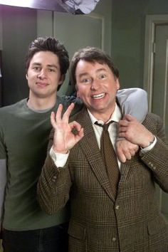 two men standing next to each other holding up their hands and making the peace sign