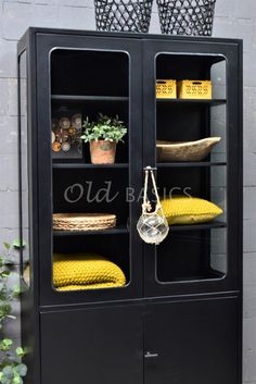 a black cabinet with yellow cushions and plants