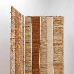 a room divider made out of woven reeds on the floor and in front of a white wall