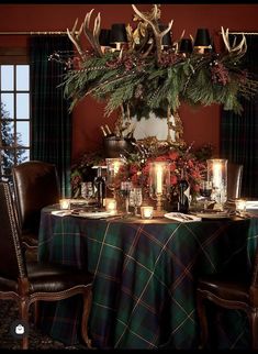 the table is set for christmas dinner with deer antlers and pine cones on it