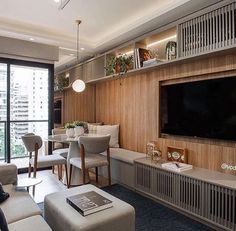 a living room filled with furniture and a flat screen tv mounted on a wall next to a window