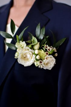 a woman wearing a blue suit and white flowers on her lapel flower bouquet is seen from the waist up