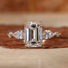 an emerald cut diamond ring with three pear shaped diamonds