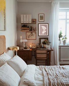 a bedroom with white linens and pictures on the wall above the bed, along with two desks