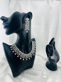 A dazzling Pink gemstone takes centerstage in this exquisite necklace set. Paired elegantly with Cubic Zirconia adding a touch of timeless glamor, mimicking the sparkle of genuine diamonds. The necklace gracefully drapes around the neck creating a captivating and versatile accessory for any occasion. Unique features:  Gemstone and Cubic Zirconia meticulously cut and polished radiates an enchanting brilliance. Style:  Ethnic and urban wear. Dress Compatibility:  Any dress with a V neckline or plu Glamorous Diamond Cut Jewelry For Party, Glamorous Diamond Jewelry With Elegant Design, Glamorous Party Jewelry With Diamond Cut, Pink Crystal Jewelry Sets For Formal Occasions, Glamorous Cubic Zirconia Jewelry With Diamond Cut, Elegant Sparkling Jewelry For Celebration, Sparkling Cubic Zirconia Jewelry For Celebration, Celebration Cubic Zirconia Jewelry Sets, Formal Pink Crystal Jewelry Sets