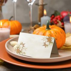 a place setting with pumpkins, candles and cards on the table for thanksgiving dinner