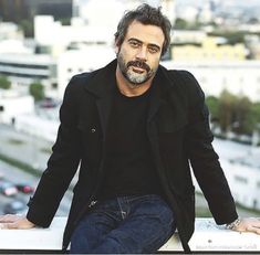 a man sitting on top of a ledge next to a city