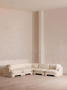 a white couch sitting on top of a hard wood floor next to a tall wall