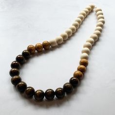 This fun necklace was hand beaded using a mix of large 25mm round dark brown, tan, and beige wooden beads in a modern color block design. The necklace measures approximately 39 inches long and is securely fastened with a silver clasp. The end result is a chic bohemian piece that fits in perfectly with today's fashion trends! Perfect for any gender. Length can be adjusted if needed - just ask! Check out more fabulous jewelry and enter my shop here: https://www.etsy.com/shop/jewelbytessyla View th Everyday Brown Jewelry With Large Beads, Handmade Brown Beaded Necklaces, Handmade Brown Round Beaded Necklaces, Brown Handmade Necklaces For Everyday Wear, Handmade Brown Necklace For Everyday Wear, Everyday Handmade Brown Necklaces, Everyday Handmade Brown Necklace, Wooden Beaded Necklaces With Round Beads, Earthy Wooden Beaded Necklaces