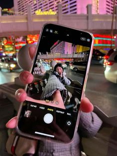 someone is holding up their cell phone to take a photo in the street at night