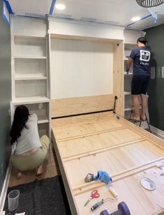 two people are working on a bed frame in a room that has been built into the wall