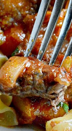 a close up of meat and vegetables on a plate with a fork sticking out of it