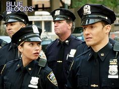 three police officers are talking to each other in front of blue bloods on the street