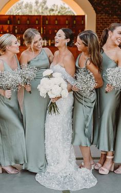 a group of women standing next to each other in front of a building holding bouquets