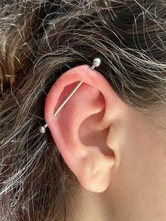 a woman's ear with two pins stuck in to the middle of her ear